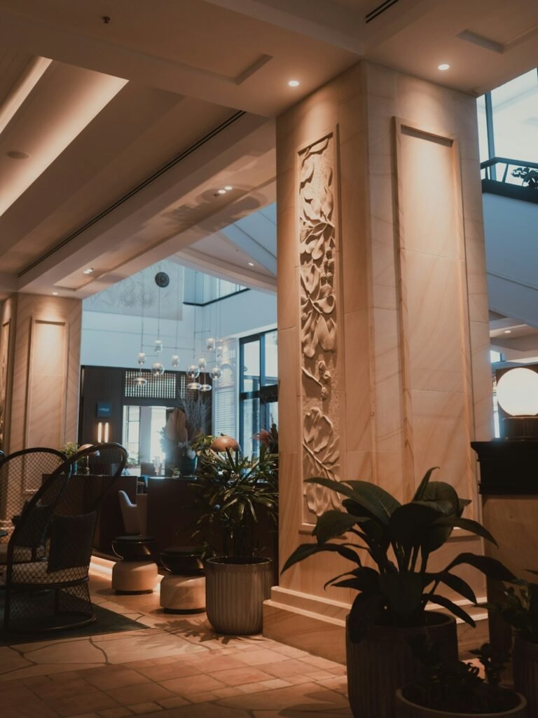 Sunlit hotel lobby with decorative pillar and plants