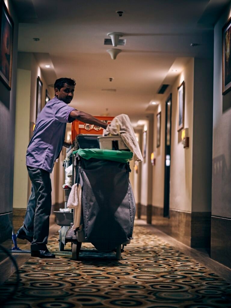 Hotel housekeeper with cleaning cart in corridor